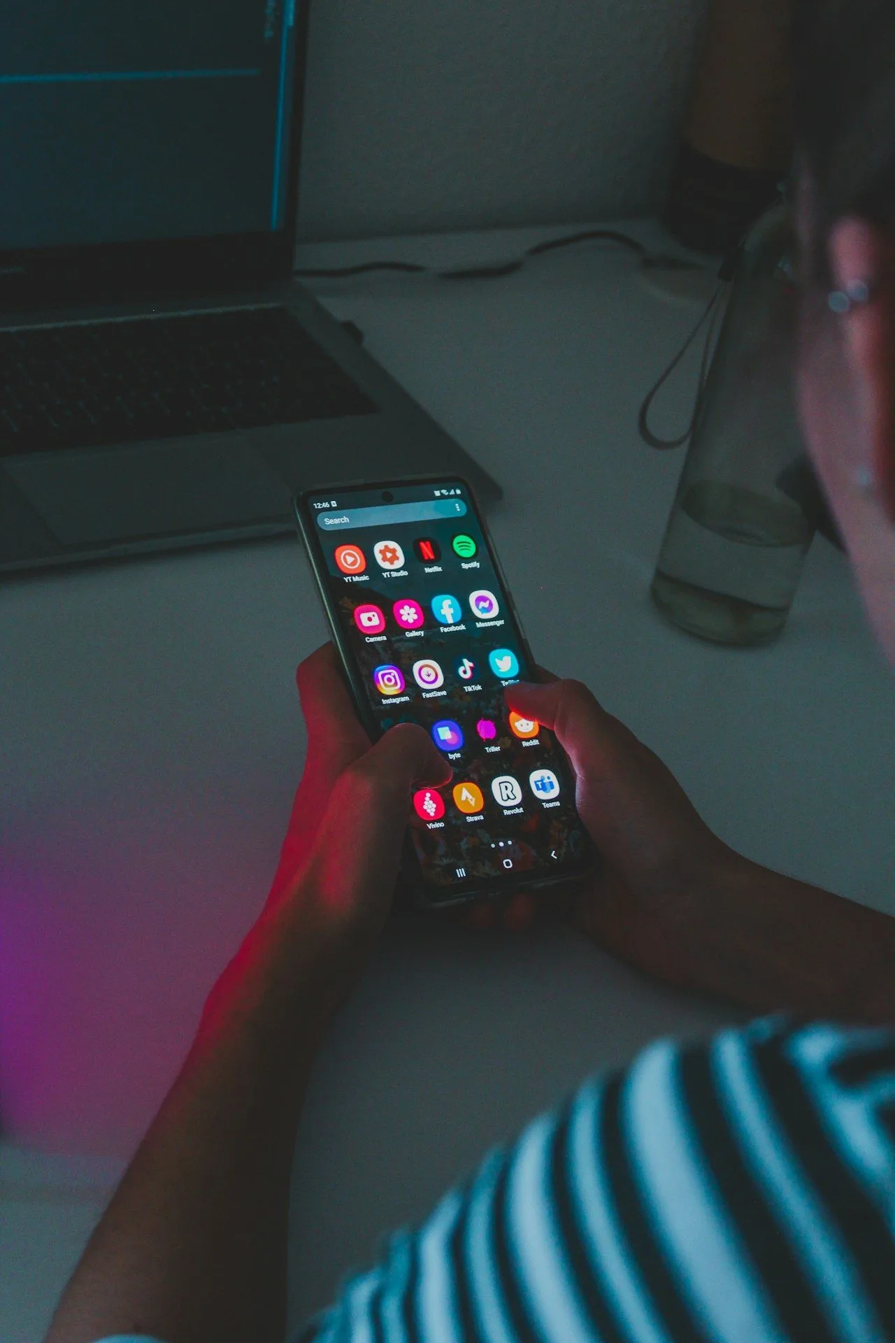 person holding black mobile phone showing icons for various social media platforms